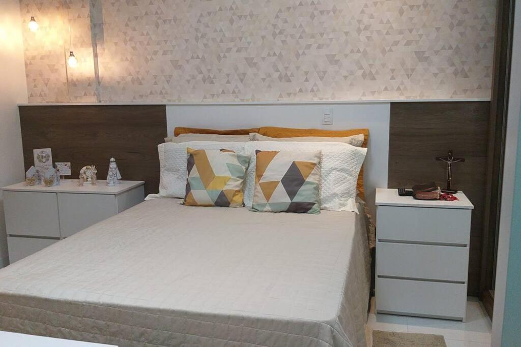a bedroom with a large white bed with pillows at Lindo Ap-Centro de Guarapari(Sem Compartilhamento) in Guarapari
