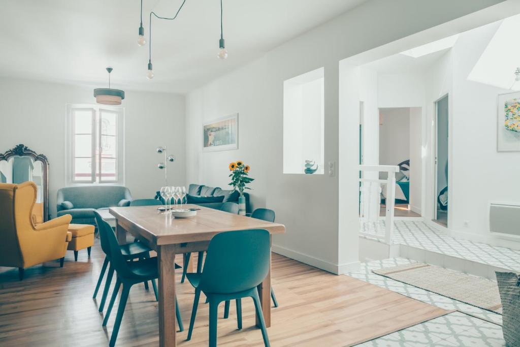 une salle à manger avec une table en bois et des chaises bleues dans l'établissement MIMOSA KEYWEEK Downtown apartment, à Biarritz