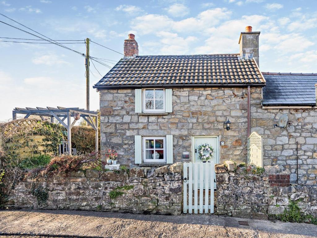 una vieja casa de piedra con una valla blanca en 1 Bed in Porthcawl 42314 en Brynmenin