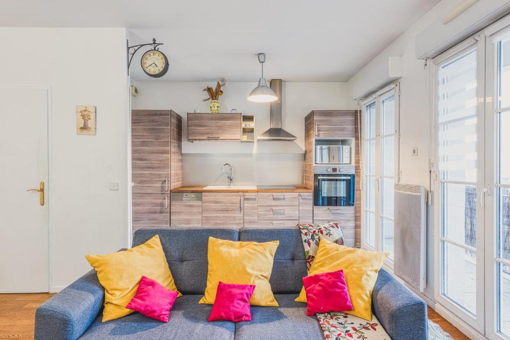 een woonkamer met een blauwe bank met gele en roze kussens bij Cocooning YourHostHelper in Serris