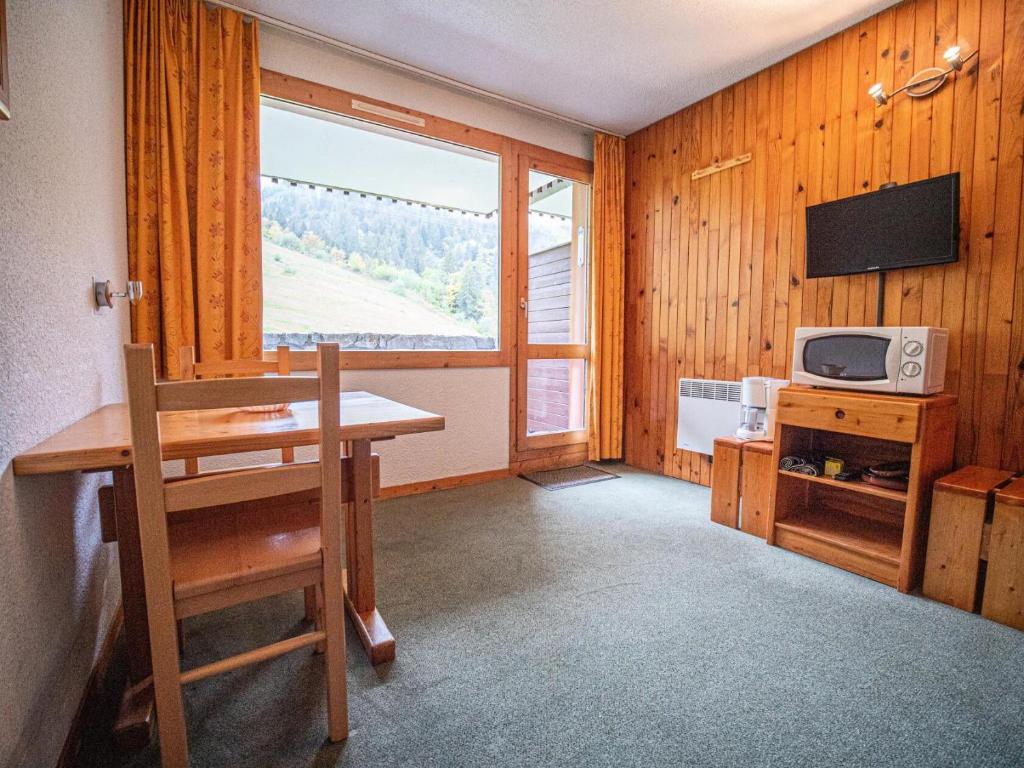 a room with a table and a microwave and a window at PORTAIL G - Appartement PORTAIL 51 pour 2 Personnes 00 in Valmorel