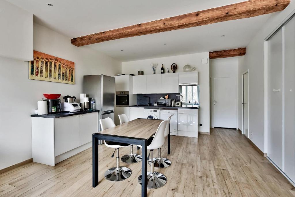 a kitchen with white cabinets and a wooden table at Somptueux saint-genois in Saint-Genis-Laval
