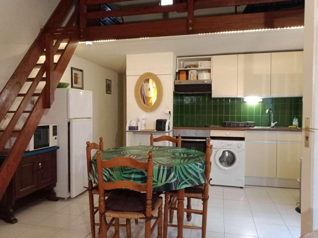 une cuisine avec une table, des chaises et un réfrigérateur dans l'établissement Villa T2 avec mezzanine, terrasse, parking privé, proche commerces et plage, calme, 6 couchages - FR-1-81-91, à Port-Leucate