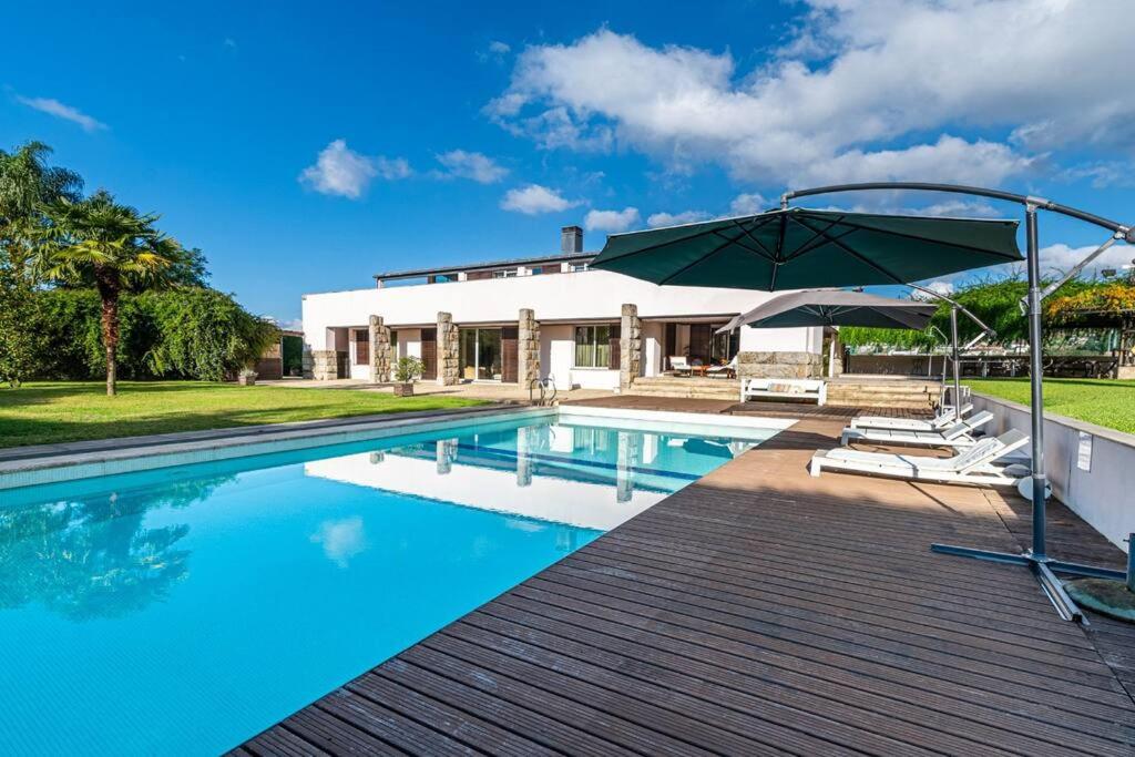 een huis met een zwembad en een parasol bij Quinta dos Miguéis in Muro