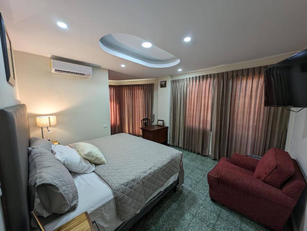 a bedroom with a bed and a red chair at Hotel Abrego in San Salvador