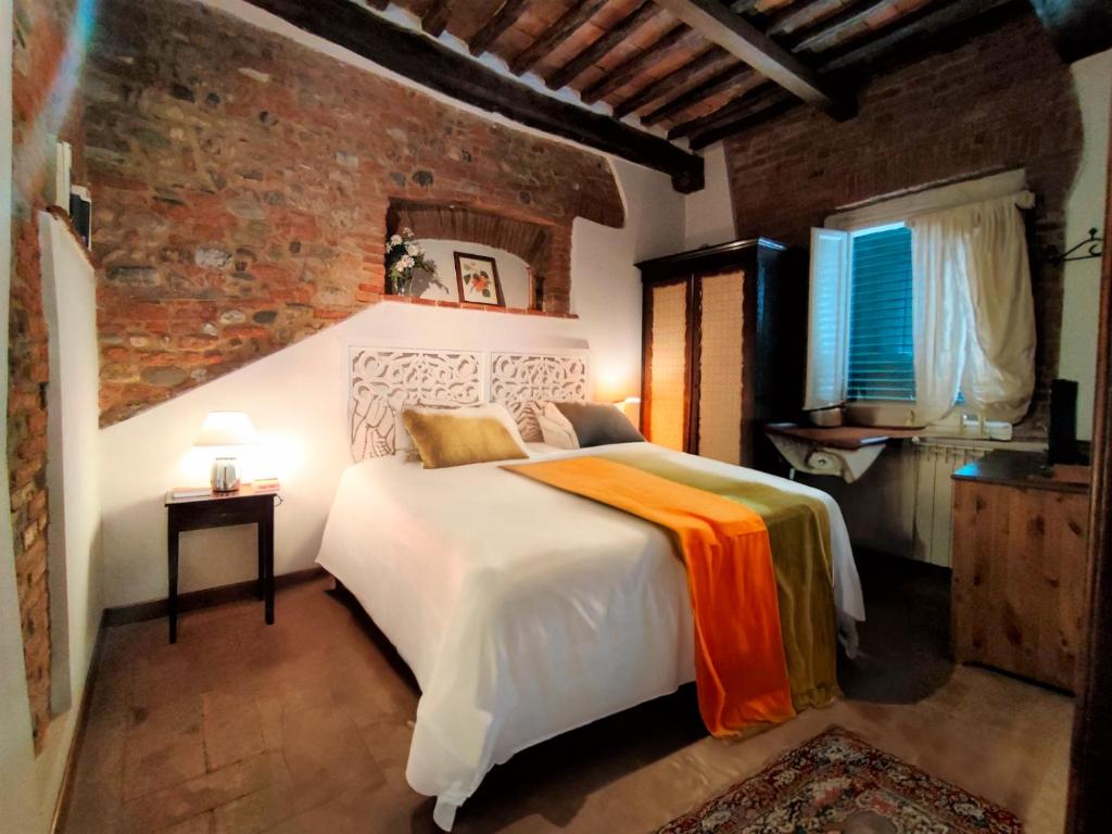 a bedroom with a white bed and a brick wall at Giada Palace Group - Sweet City Center Apartment in Lucca