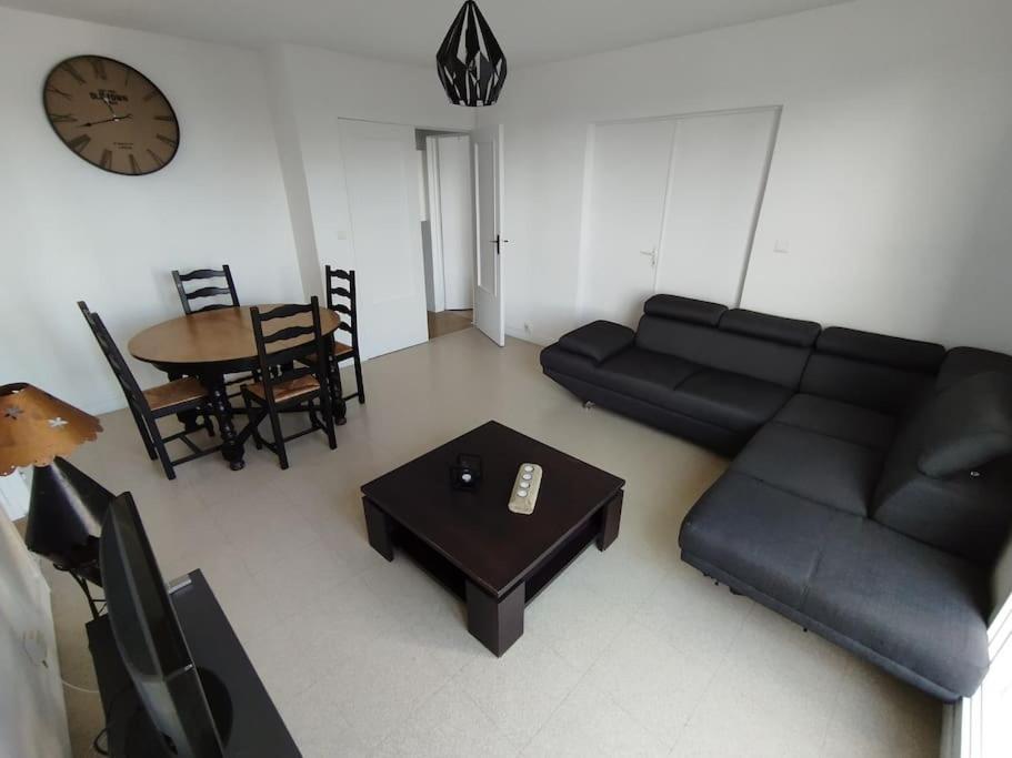 - un salon avec un canapé, une table et un réveil dans l'établissement Appartement proche stade et parc expo (2), à Nantes