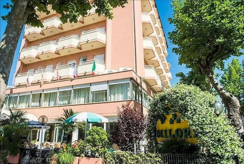 a tall pink building with an umbrella in front of it at Hotel Milord in Cesenatico