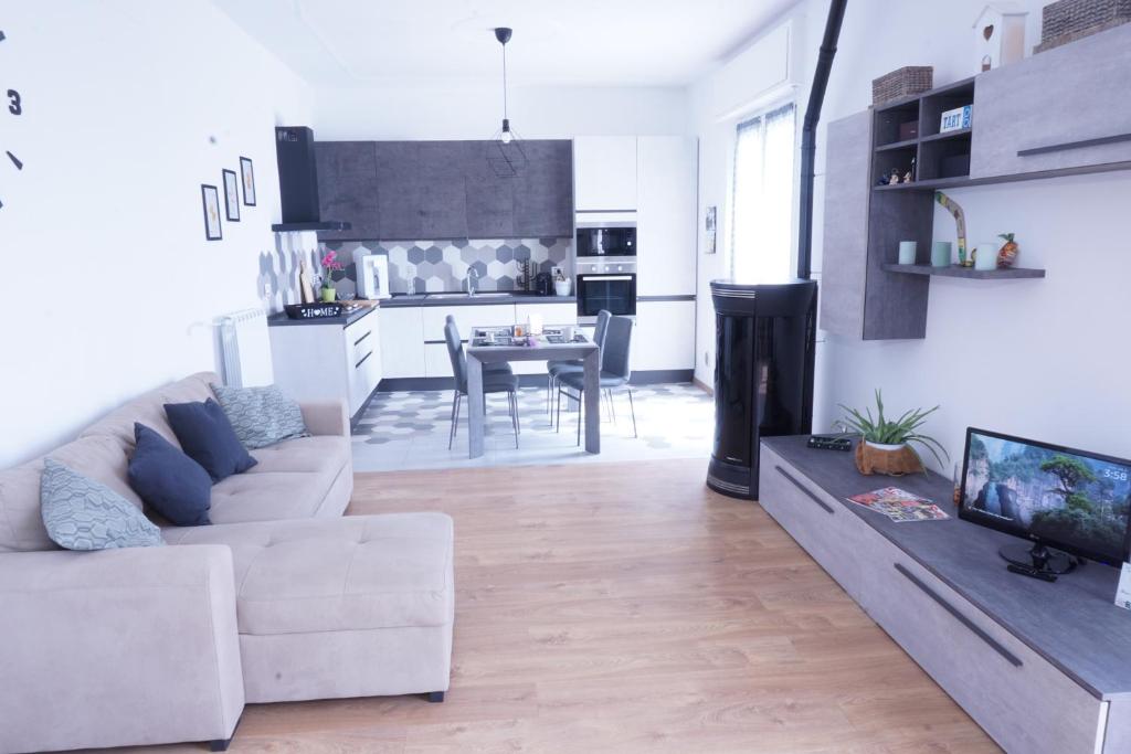 a living room with a white couch and a kitchen at Casa Bellavista-Spazioso appartamento in collina a due passi da Bergamo in Sorisole