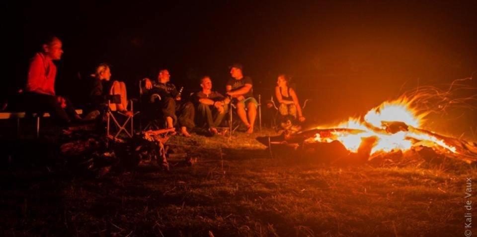 a group of people sitting around a fire at night at Thagoona Shady River Camp in Thagoona