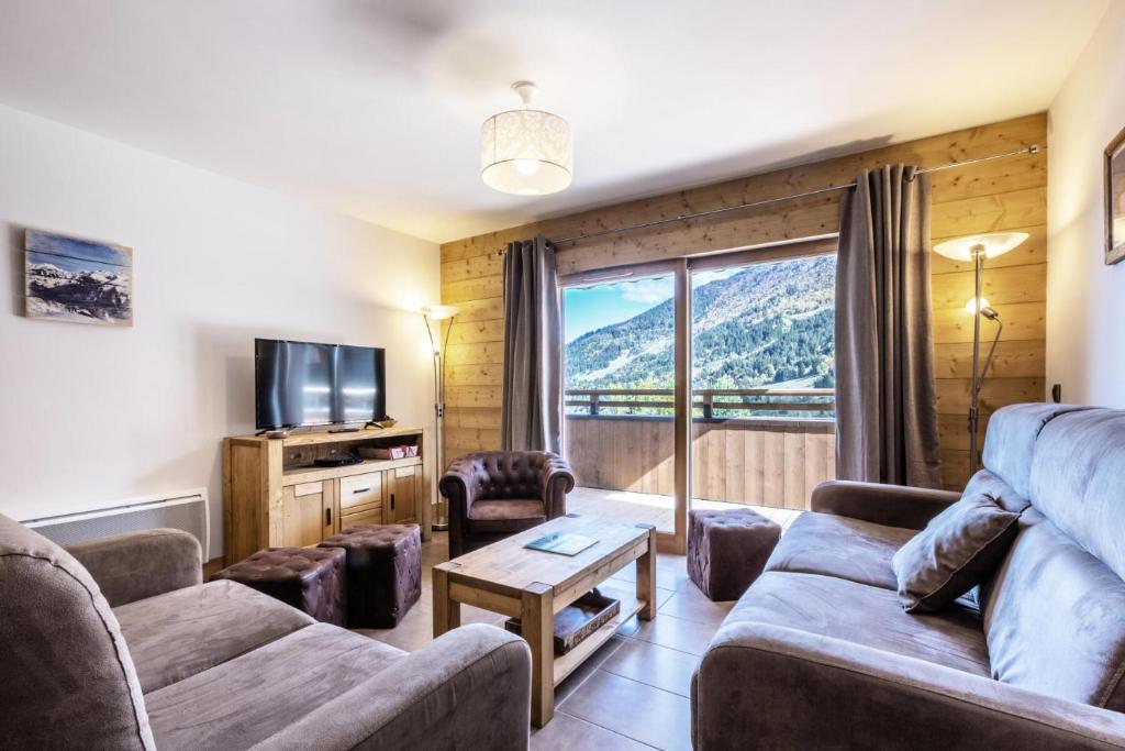 a living room with a couch and a tv at Résidence LA GRANGE AUX FEES - Appartement GRANGE AUX FEES E04 pour 8 Personnes in Valmorel