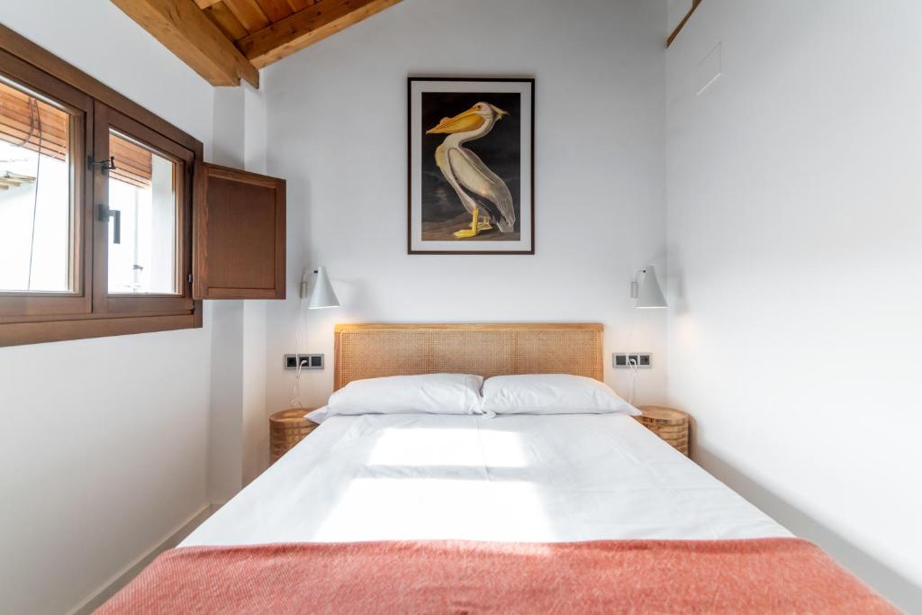 a bedroom with a bed with a bird picture on the wall at Caleffa Triunfo 1 in Granada