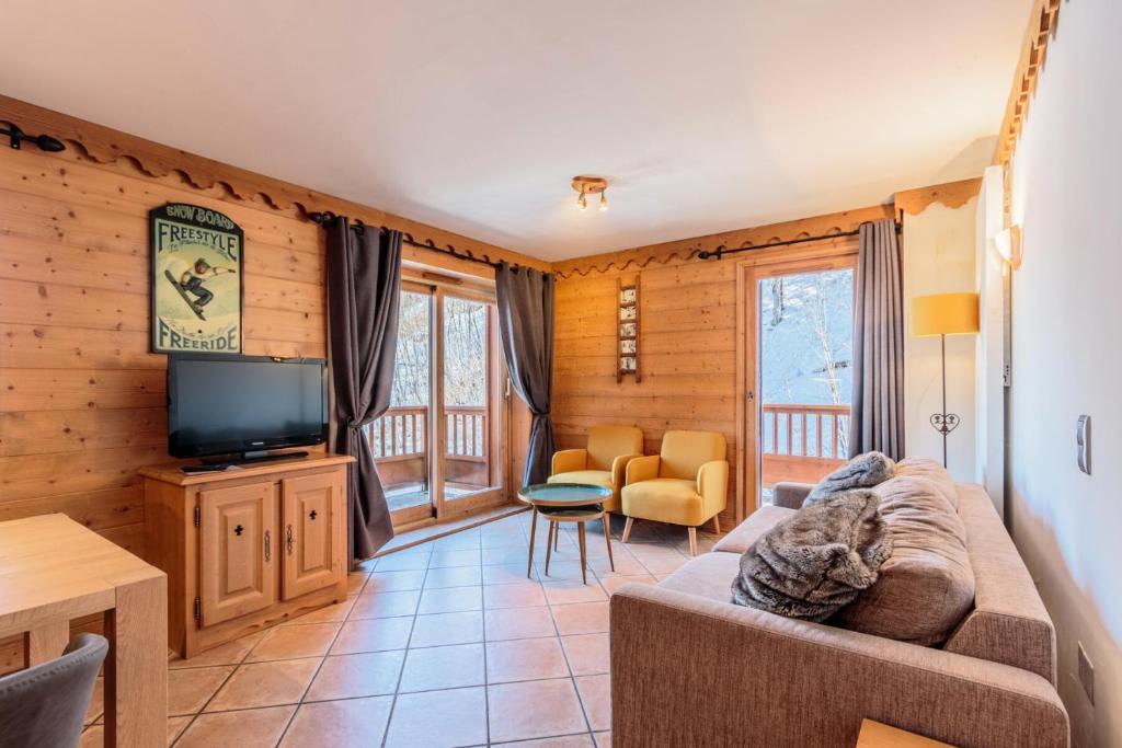 a living room with a couch and a television at Les Chalets du Gypse - Appartement LES CHALETS DU GYPSE C07 pour 6 Personnes 944 in Saint-Martin-de-Belleville
