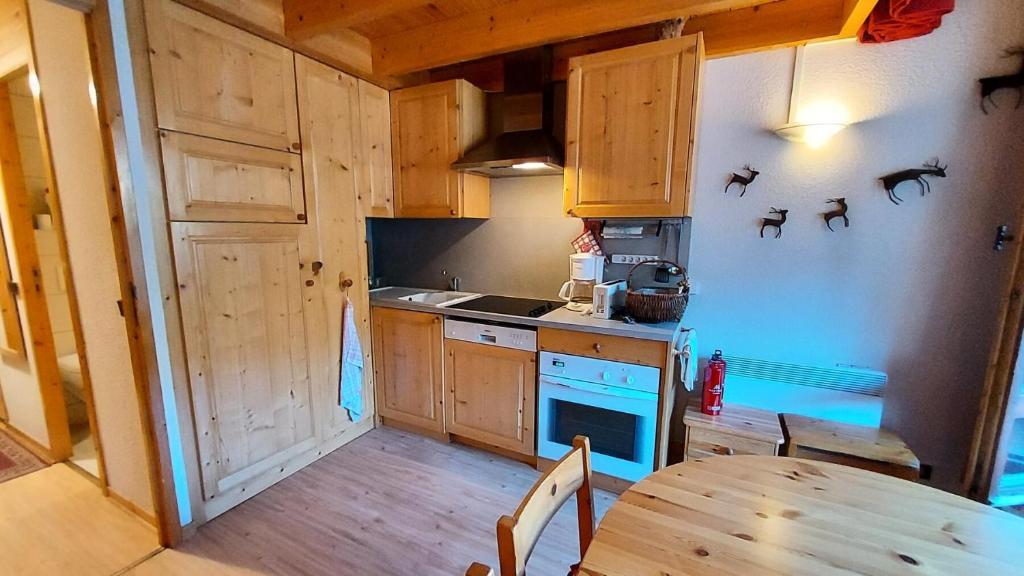 a kitchen with wooden cabinets and a table in it at MUCILLON G - Appartement MUCILLON 794 in Valmorel