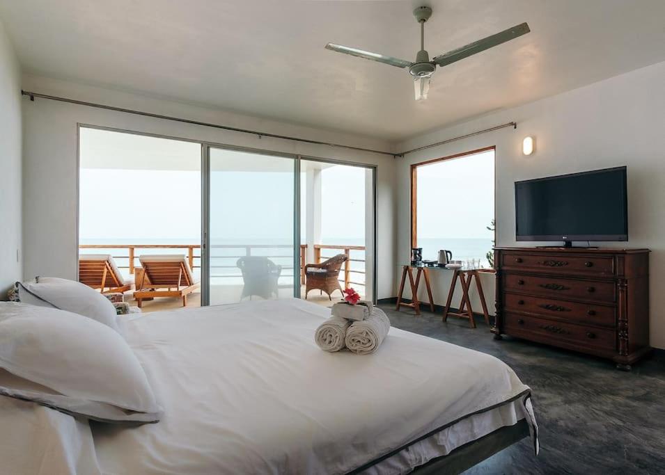 a bedroom with a large bed and a flat screen tv at Marmot Seashore Moonset Suite in Máncora