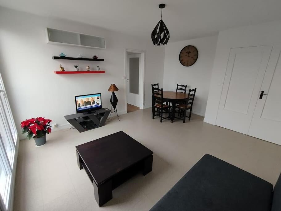 un salon avec une table et une télévision dans l'établissement Appartement Courbaril à Nantes (6), à Nantes