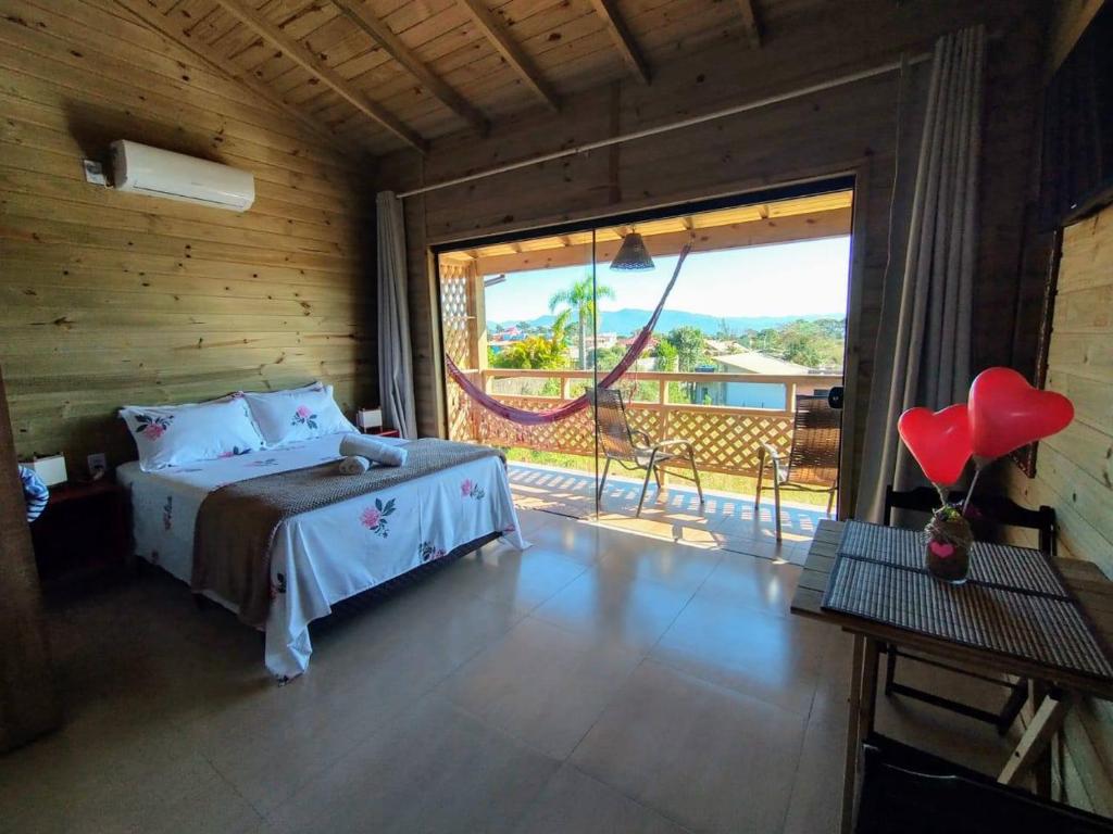 a bedroom with a bed and a large window at SUÍTES PRAIA DO ROSA in Imbituba