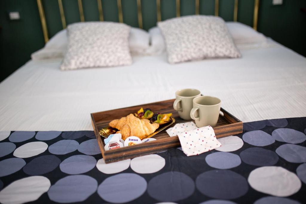 a tray with food and cups on a bed at Bologna Travel Suite in Bologna