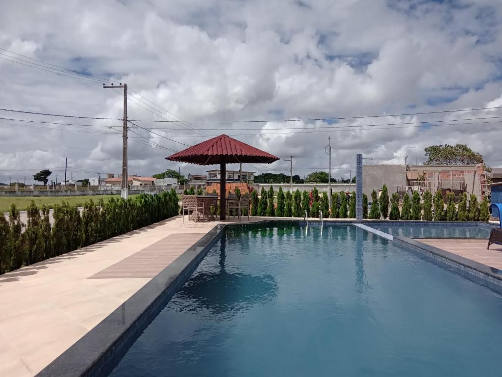 uma piscina com um guarda-sol, uma mesa e cadeiras em Seu espaço aconchegante em Bananeiras-pb em Bananeiras