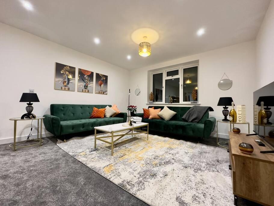 a living room with a green couch and a table at Brand new modern Cheltenham home 