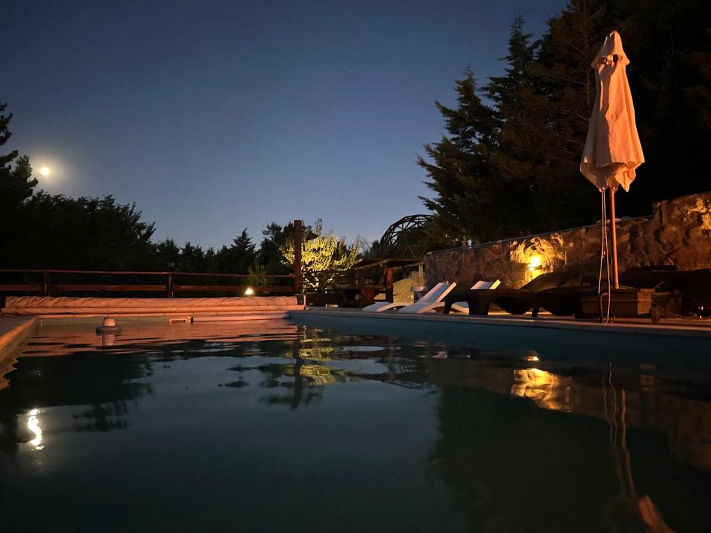 einen Swimmingpool in der Nacht mit Sonnenschirm in der Unterkunft Altos del Cordón in Comodoro Rivadavia