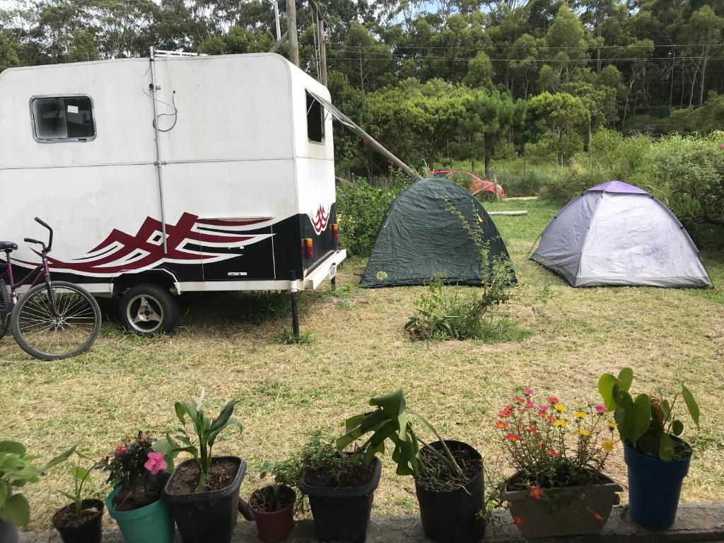 przyczepa i namioty na polu z roślinami w obiekcie Camping Refúgio Shakti II w mieście Florianópolis
