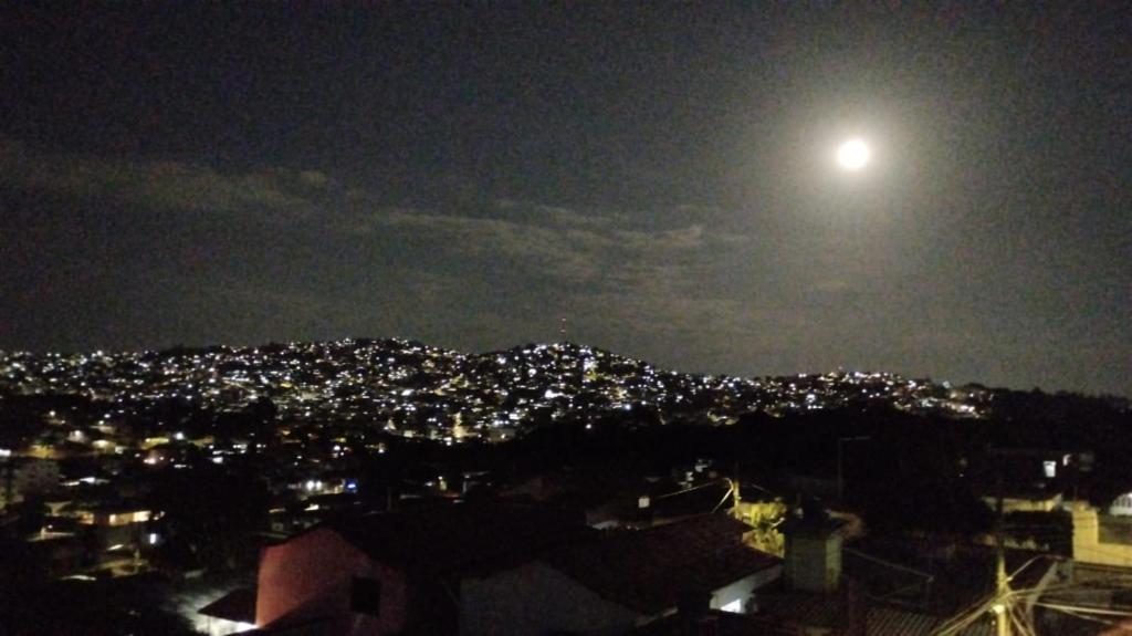 uma lua cheia a subir sobre uma cidade à noite em Fine Guest em Belo Horizonte