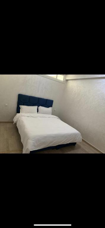 1 dormitorio con cama blanca y cabecero azul en Jolie appartement avec terrasse, en Casablanca