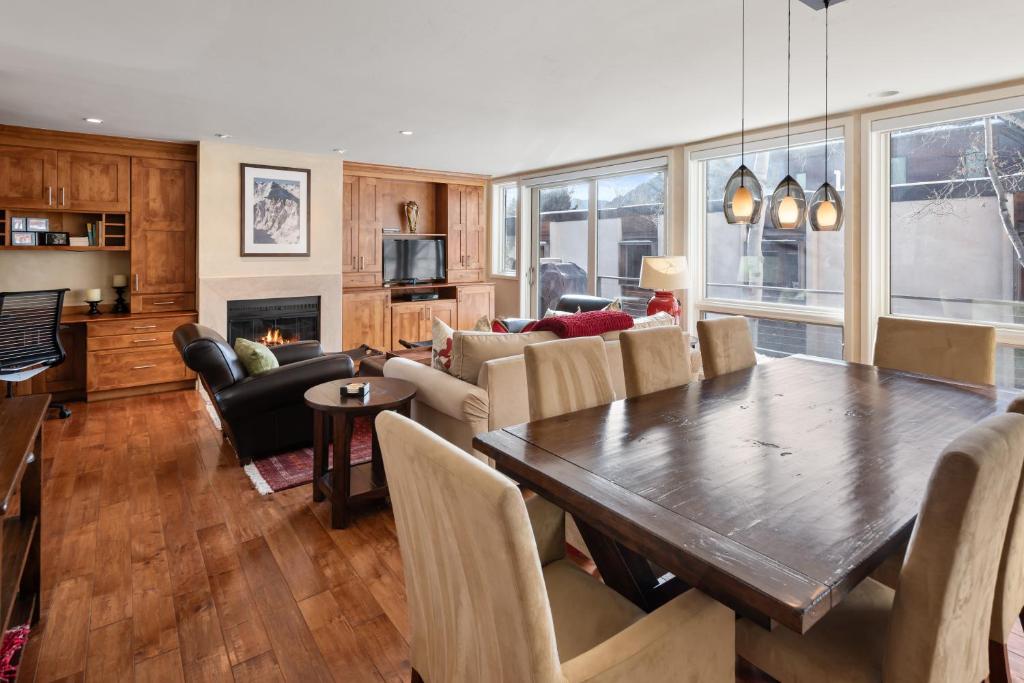 a living room with a wooden table and a dining room at Spring Street Unit 629, 2BR Condo w/ Mountain Views and Door Step Access to Shops & Restaurants in Aspen