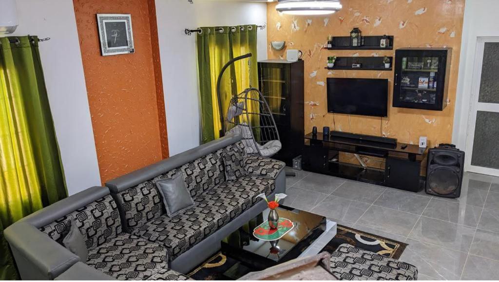 een woonkamer met een bank en een televisie bij Refuge celeste : Votre Havre Numerique in Lomé