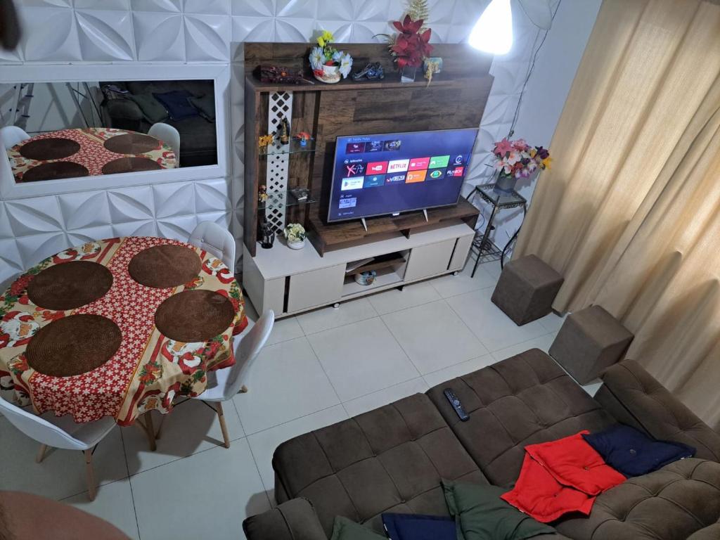 un salon avec une table et une télévision dans l'établissement Apto Enseada, 2 quadras da praia - 2 quartos com ar condicionado - 6 hospedes, à Guarujá