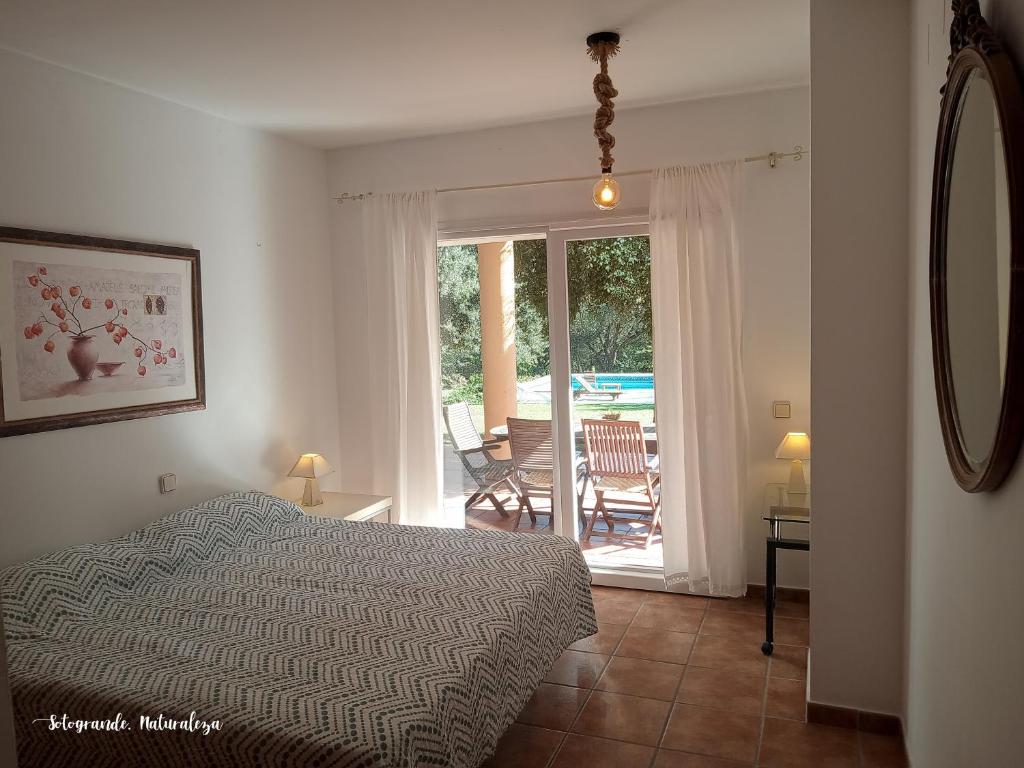 a bedroom with a bed and a view of a patio at Sotogrande - Estancia en plena naturaleza - Abril in Sotogrande
