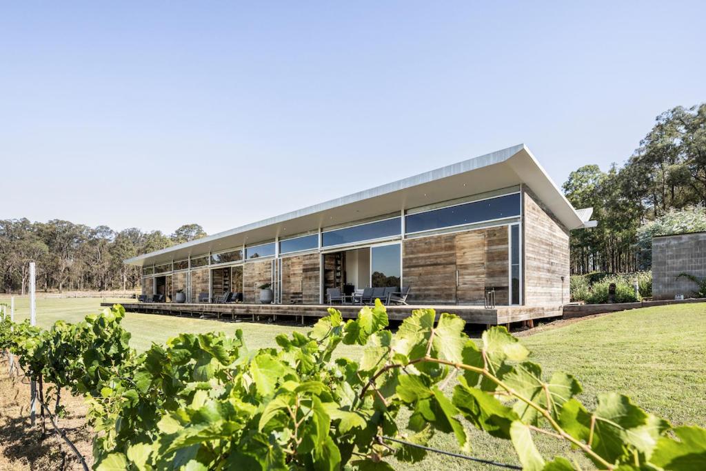 a house with large windows and a grass field at The Longhouse - Suite 3 in Pokolbin