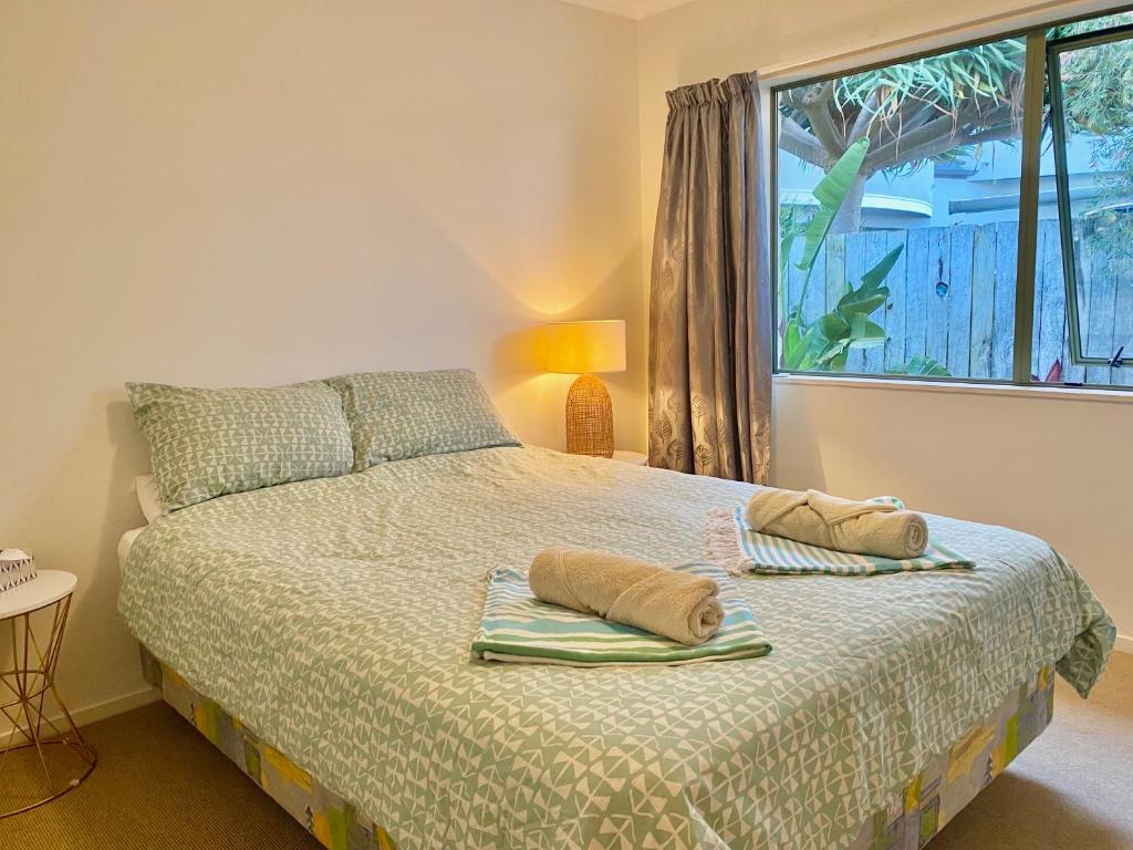a bedroom with a bed with two pillows on it at Sanddune Delight in Papamoa