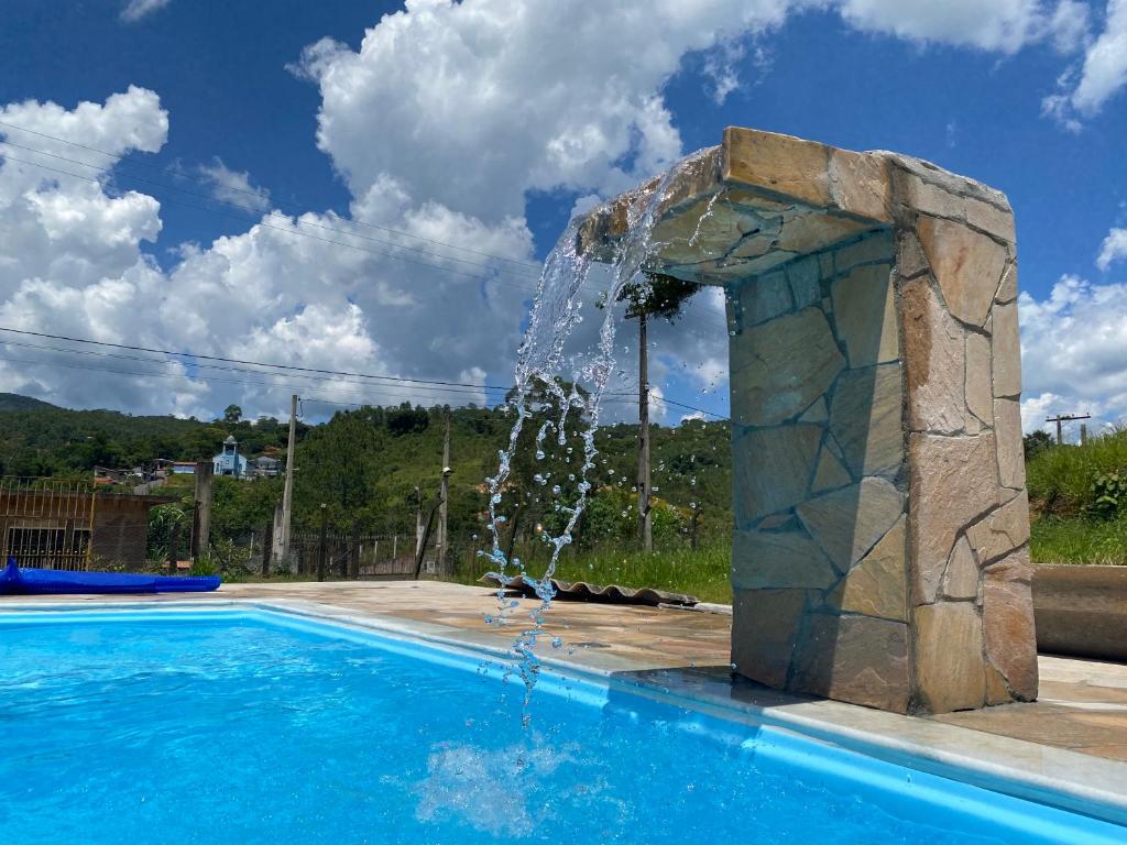a swimming pool with a water fountain at Excelente casa com piscina próximo SP in Nazaré Paulista