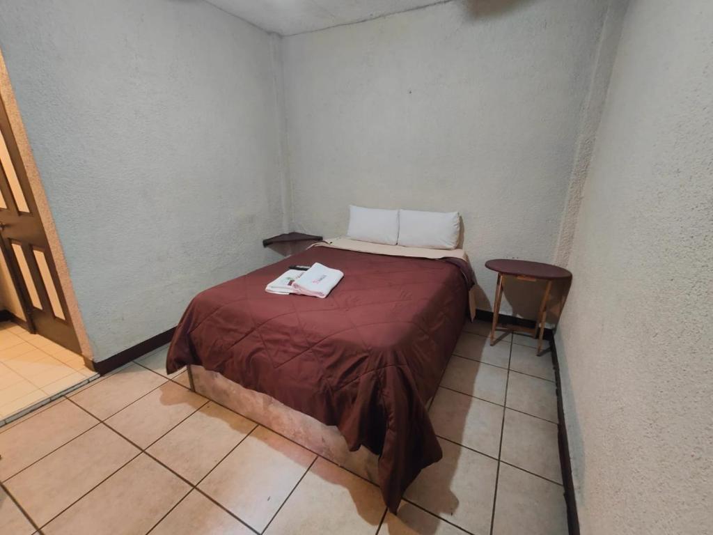 Cama pequeña en habitación pequeña con mesa en Hotel Chinesca en Mexicali