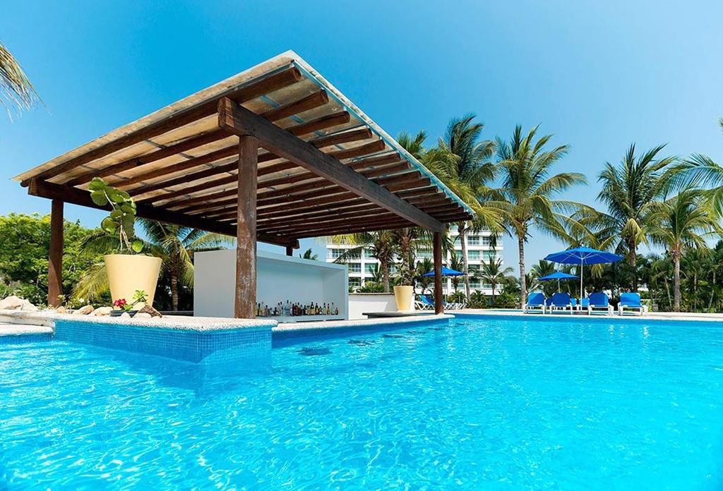 a swimming pool with a wooden pergola in a resort at Condo Mayan Lakes in Acapulco