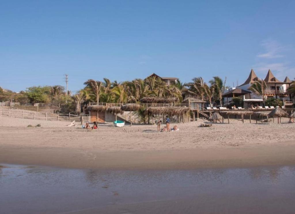 a beach with palm trees and people on the sand at La Cabaña del Mar Vichayito in Vichayito