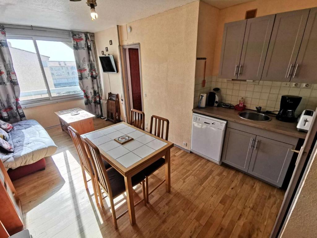 une petite cuisine avec une table et une table et des chaises dans l'établissement Résidence Terrasses De La Mediterranee 1 - 2 Pièces 4 couchages PORT LEUCATE MAE-4654, à Port-Leucate