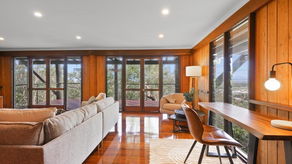 a living room with a couch and a table and chairs at Rainforest Treehouse Sanctuary - with ocean views in Smithfield