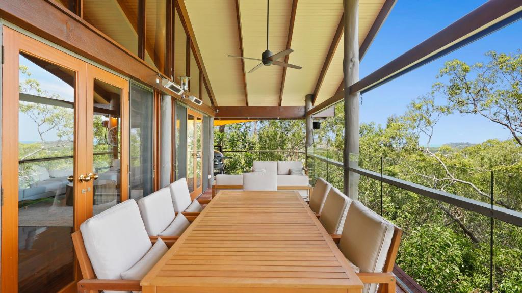a porch with white chairs and a wooden table at Rainforest Treehouse Sanctuary - with ocean views in Smithfield