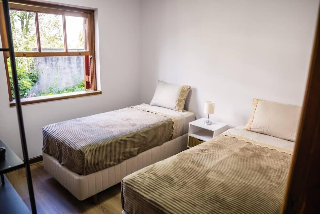 een slaapkamer met 2 bedden en een raam bij Quatro Estações Hospeda L 11 - Conforto para família no Capivari in Campos do Jordão