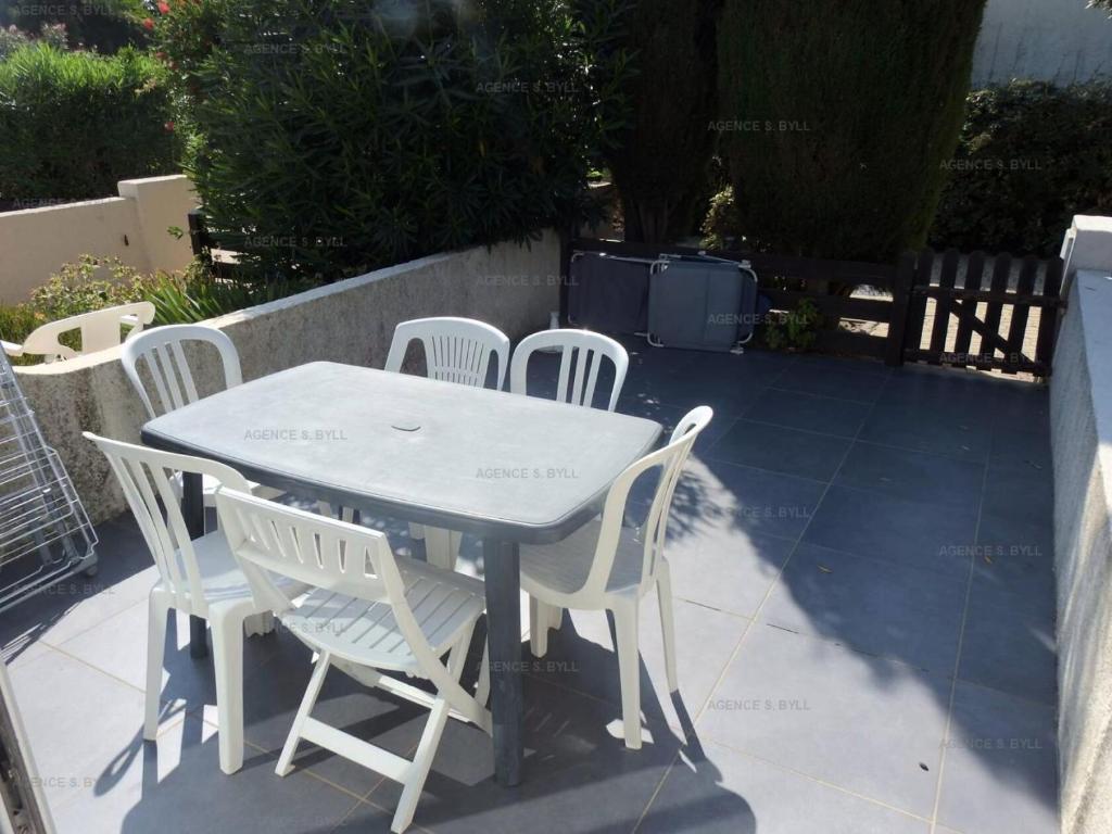 einen weißen Tisch und Stühle auf einer Terrasse in der Unterkunft Résidence Héliovillage - Maisons & Villas pour 4 Personnes 804 - Naturiste in Cap d'Agde
