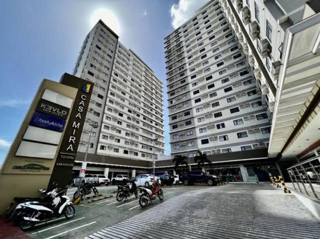 two tall buildings with motorcycles parked in a parking lot at Kristinas Homestay- Cozy Resort Vibe Condotel in Cebu City