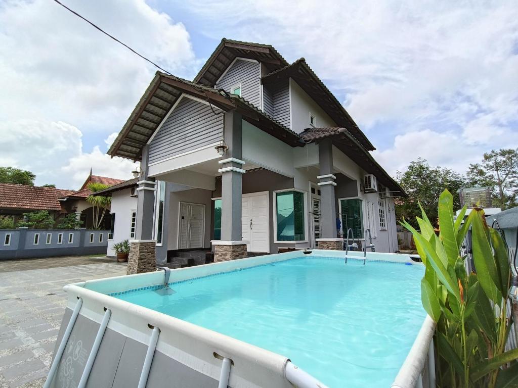 a house with a swimming pool in front of it at Awang's Villa Homestay in Kampong Gong Badak