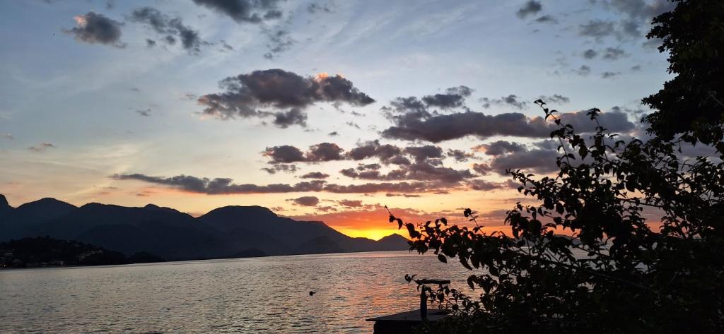 a sunset over a body of water with mountains at Recanto das tartarugas in Mangaratiba