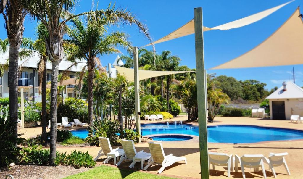 una piscina con sillas y sombrillas blancas en Mercure Bunbury Sanctuary Golf Resort en Bunbury