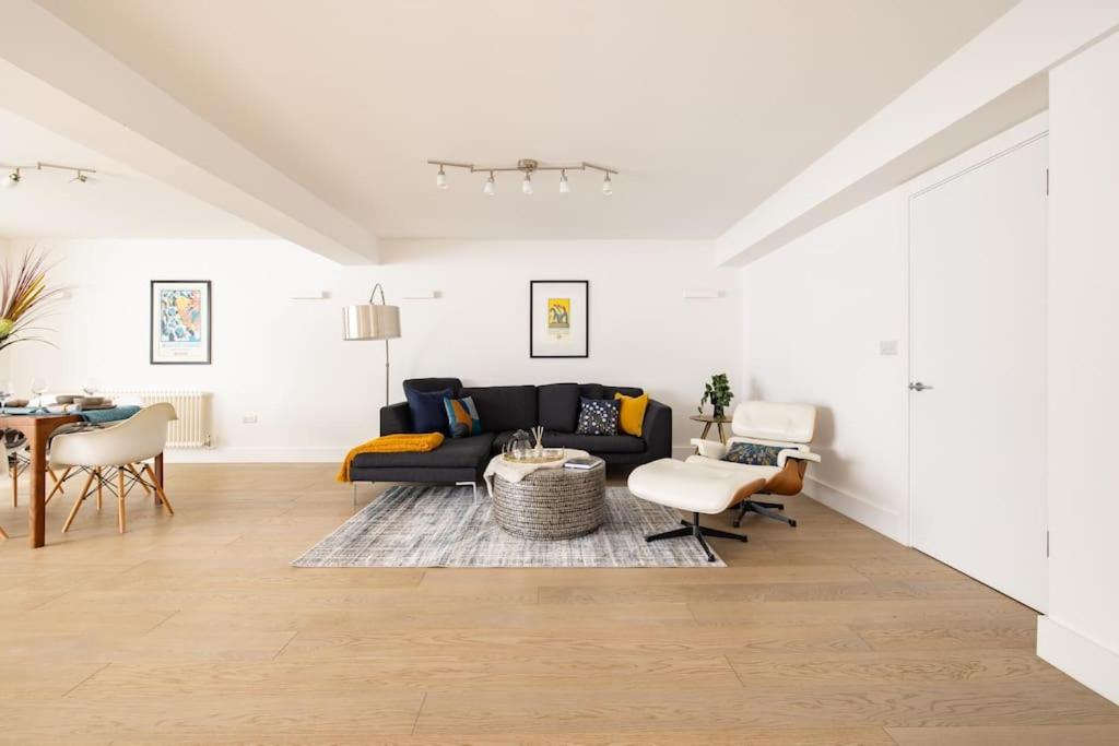 sala de estar con sofá negro y mesa en Wild Roses Serviced Apartments - Borough, en Londres