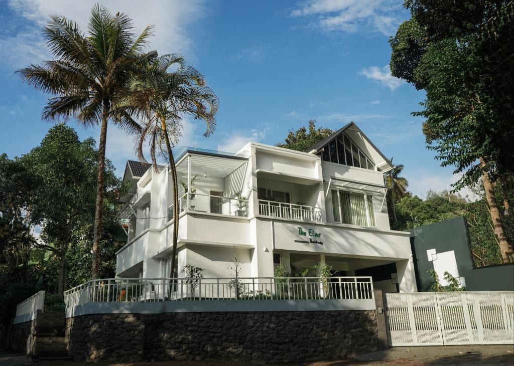 a white building with a palm tree in front of it at The Elms Thekkady in Thekkady