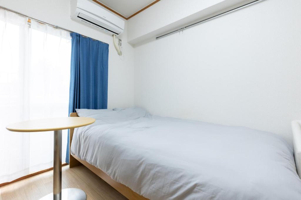 a bedroom with a bed and a table and a window at Inoguchi View Heights in Itsukaichi